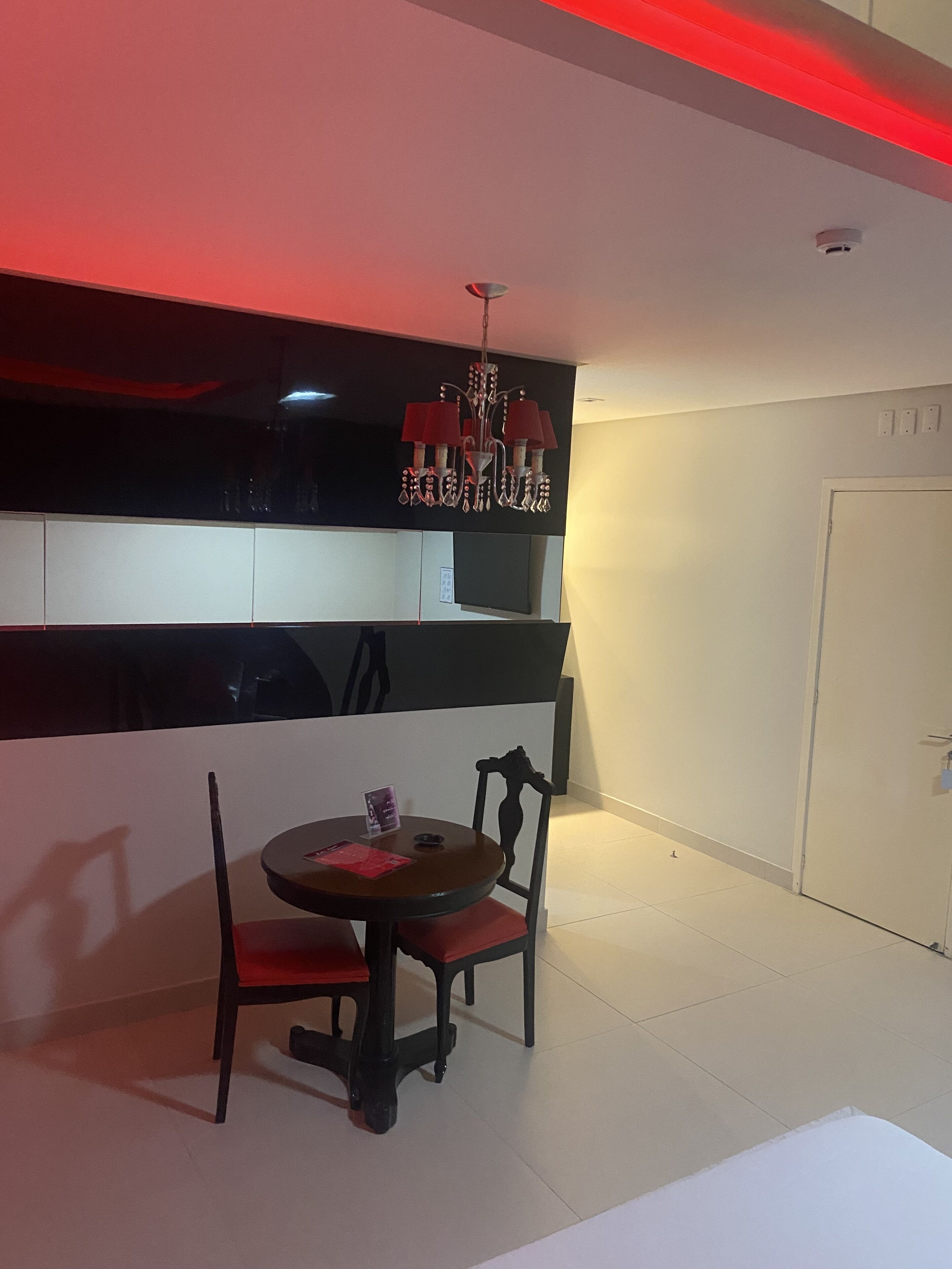 Uma sala de jantar com uma mesa redonda, duas cadeiras e um candelabro.