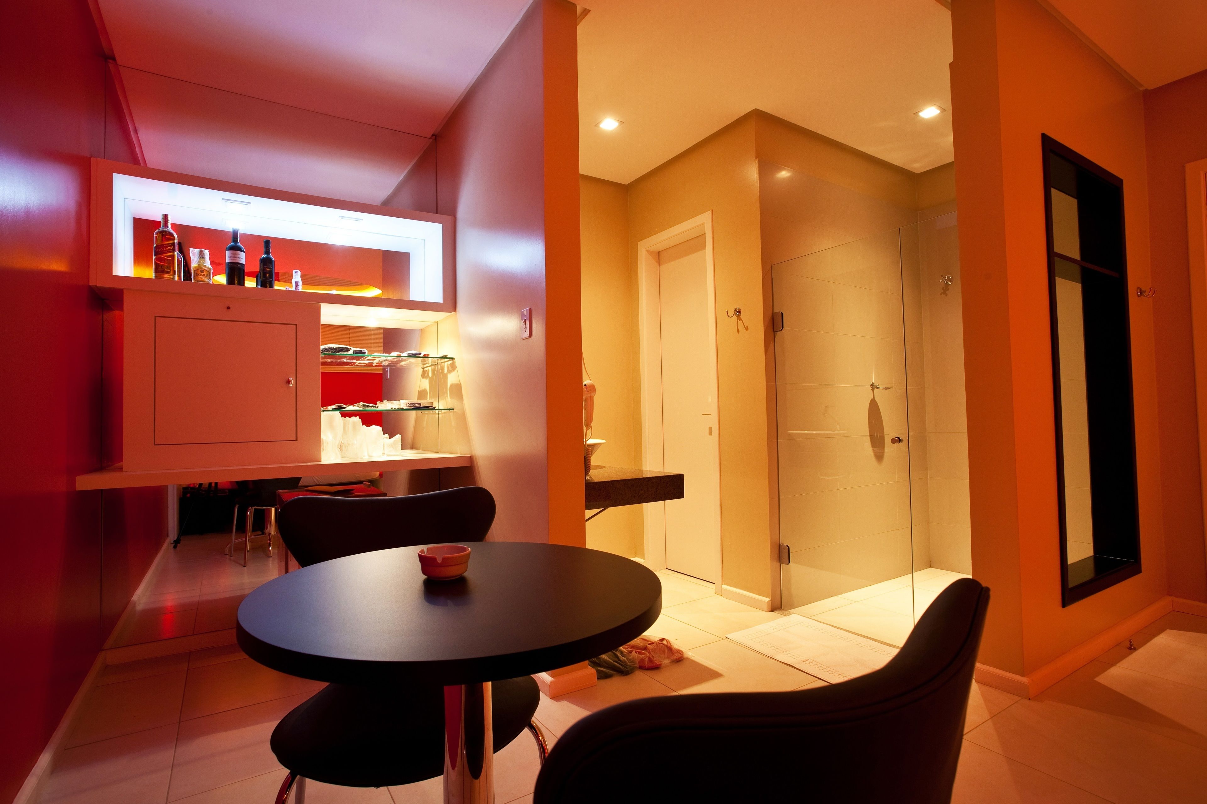 Una cocina moderna con comedor, cabina de ducha de vidrio y puerta que da a un baño.