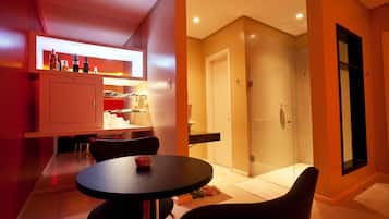 Una cocina moderna con comedor, cabina de ducha de vidrio y puerta que da a un baño.