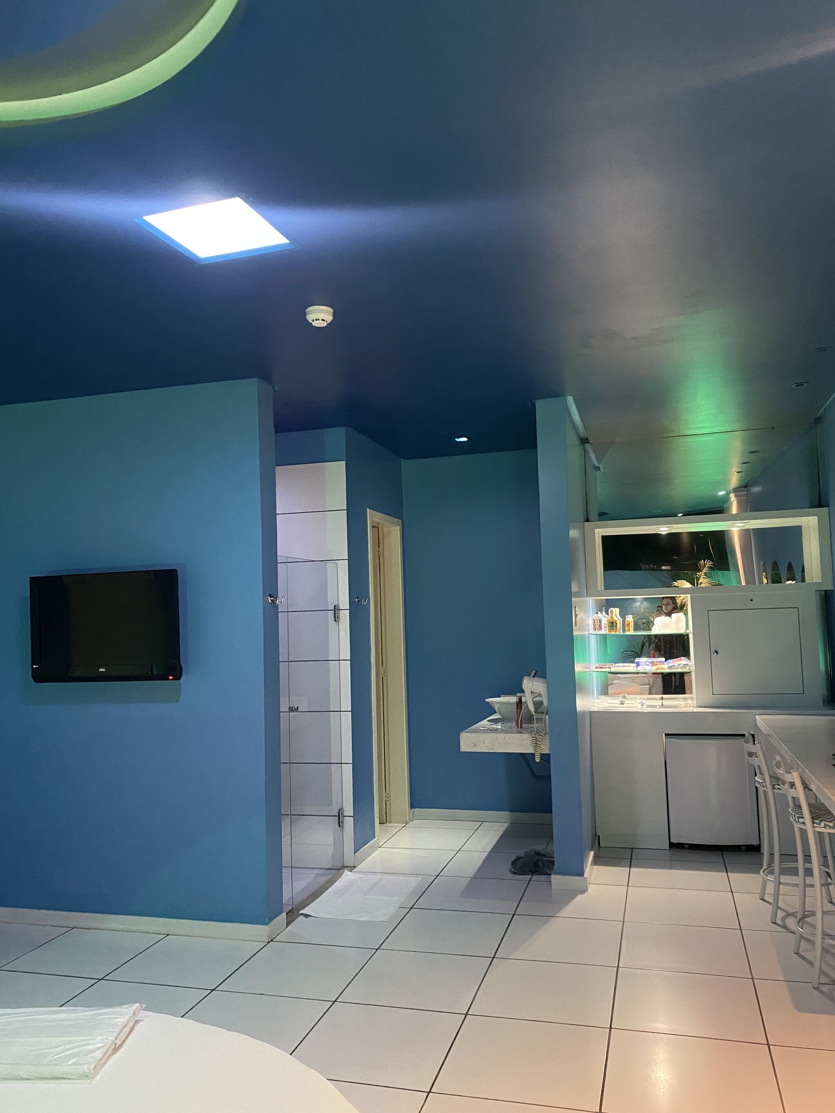 Una cocina moderna con paredes azules, un refrigerador empotrado y un televisor de pantalla plana montado en la pared.