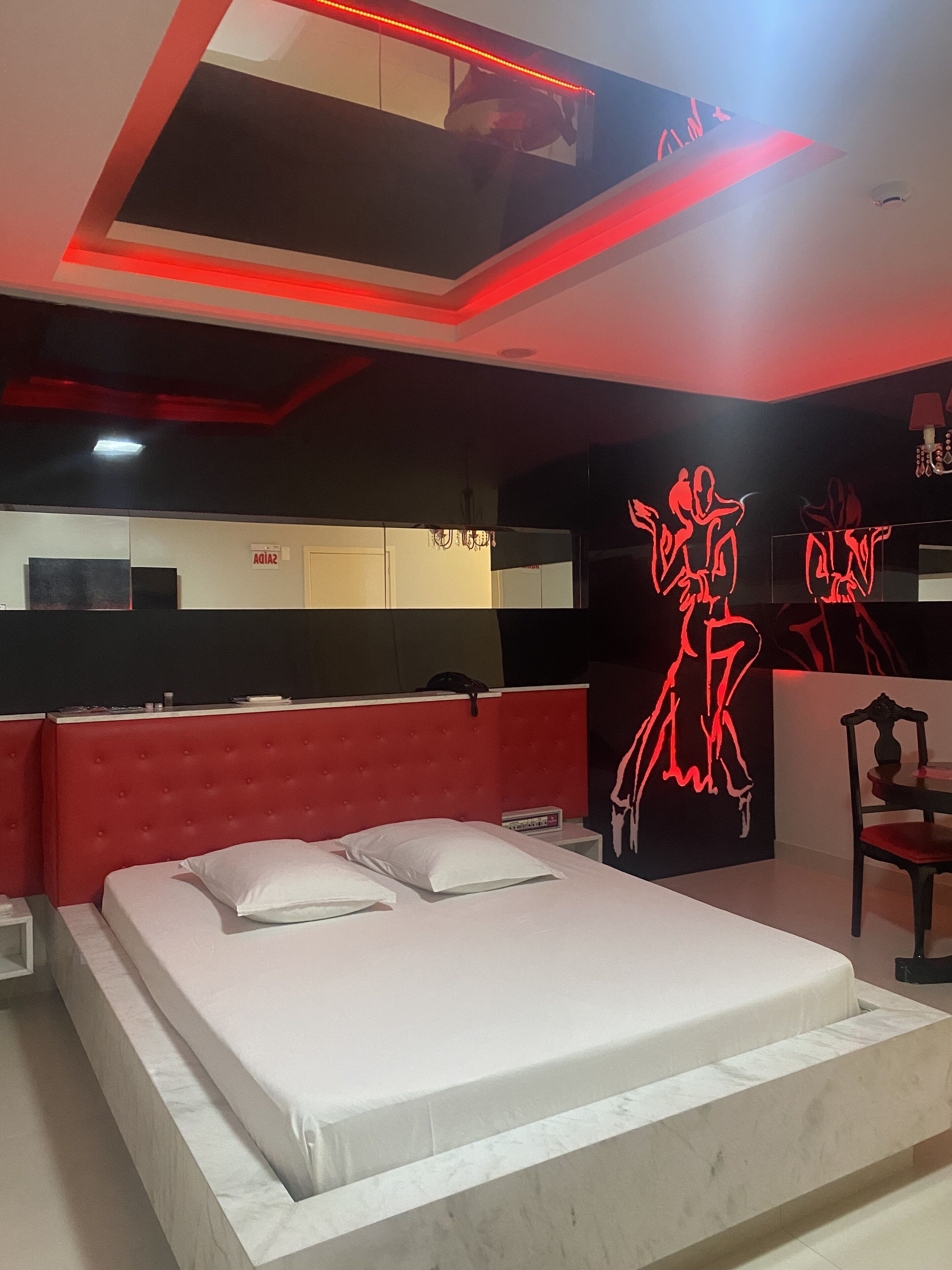Una camera da letto moderna con una testiera rossa, un letto grande e una parete con arte neon rossa.