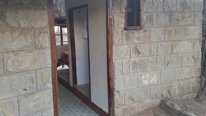 A room with a bed, a window, and a door leading to another room.