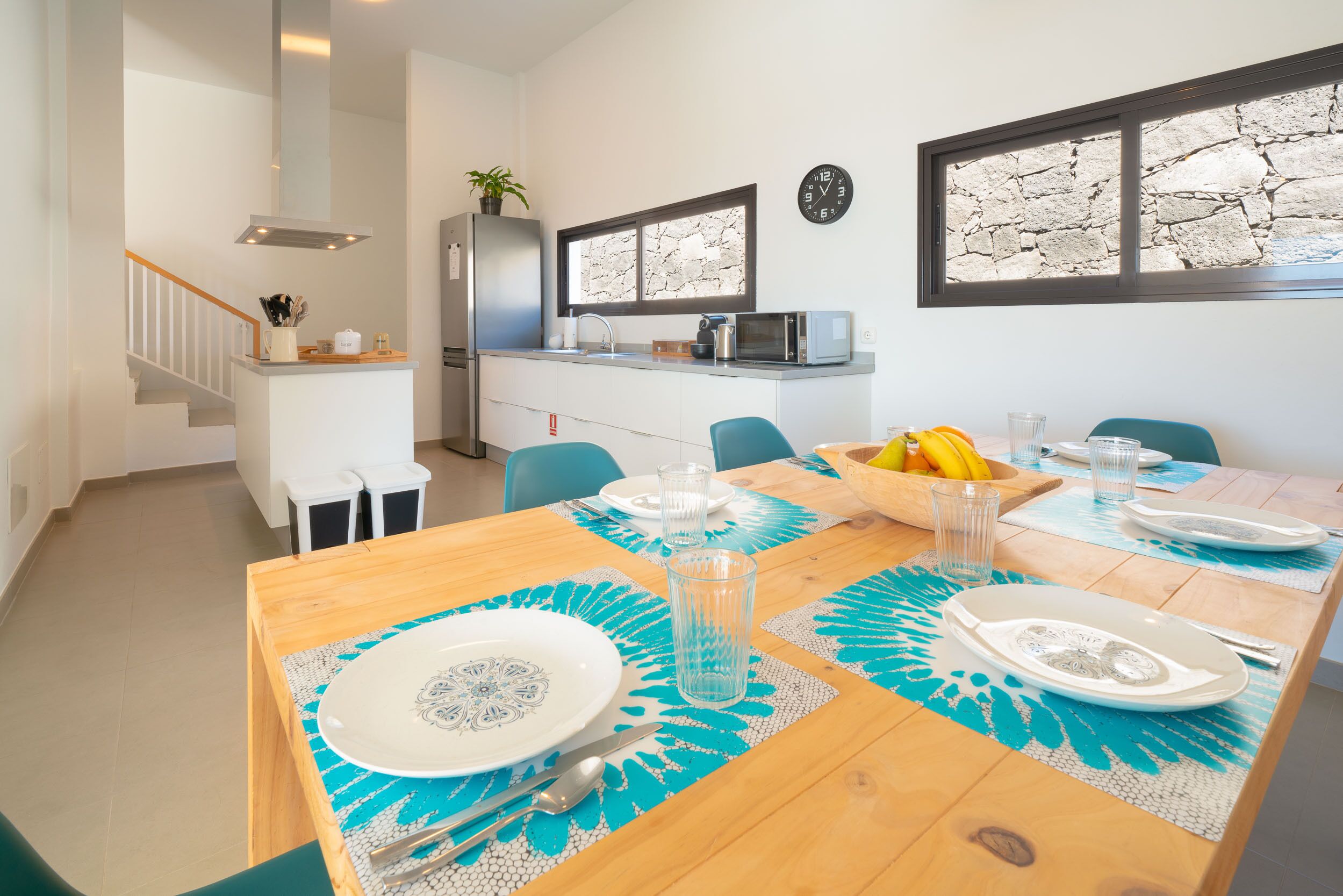 A modern kitchen with a built-in microwave, a refrigerator, and a window with a stone-like design.