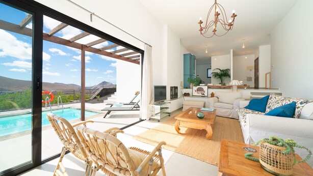 A spacious living area with a large window, a pool, and a view of the mountains.