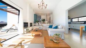 A modern living room with a sofa, coffee table, and a dining area.