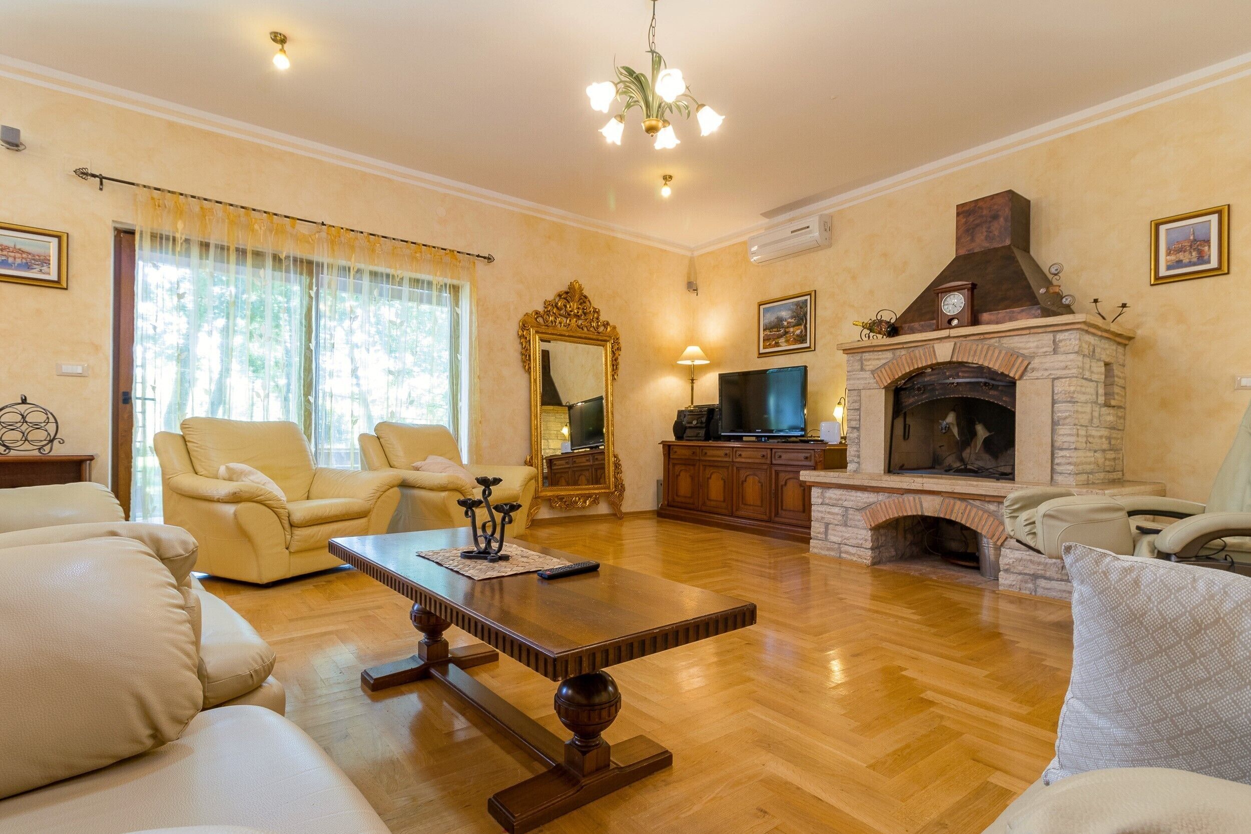 A living room with a fireplace, leather sofas, a wooden coffee table, and a television.