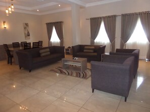 A modern living room with a sofa set, a coffee table, and a dining area with chairs.