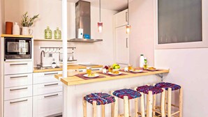 A modern kitchen with a built-in oven, a sink, and a bar area with stools.
