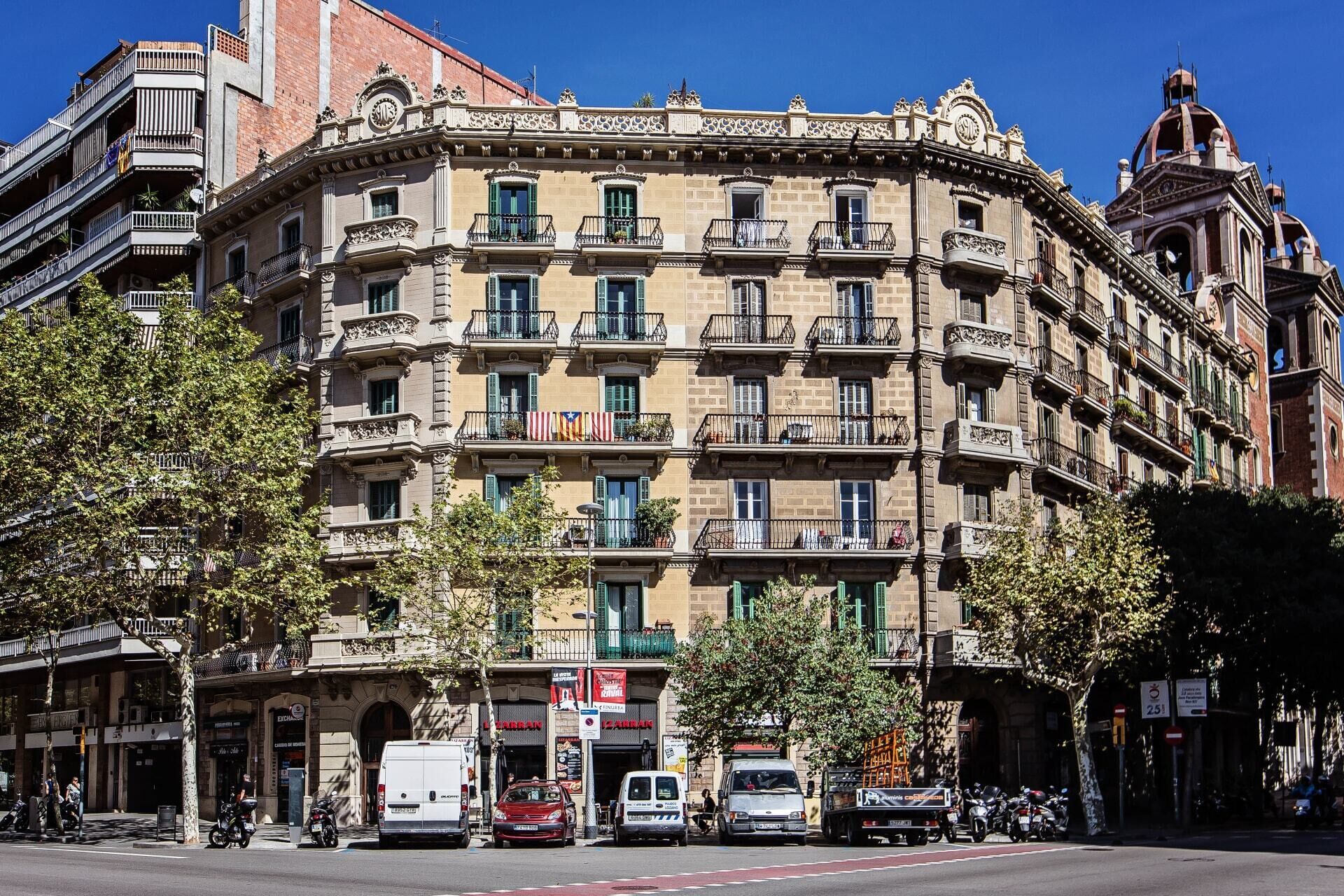 Un immeuble à plusieurs étages doté de balcons, d’une horloge et d’un auvent rayé de rouge et de blanc.