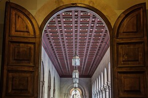 Un couloir avec des portes en bois et un plafond orné de motifs.