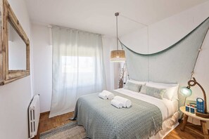 Une chambre à coucher avec un lit, un fauteuil suspendu, une table de chevet avec une lampe et un radiateur.