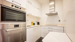 A modern kitchen with stainless steel appliances, white cabinetry, and a built-in oven.
