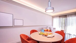 Uma zona de refeições moderna com uma mesa redonda, cadeiras vermelhas e um candeeiro no teto.