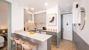 A modern kitchen with a central island, bar stools, and a dining area.