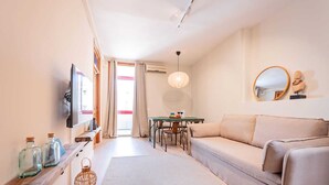 Een moderne woonkamer met een bank, een eettafel en een aan de muur bevestigde televisie.