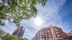 Un immeuble résidentiel à plusieurs étages, doté de balcons, entouré d’arbres et baigné par un ciel dégagé.