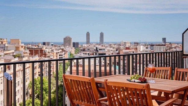 Un balcon avec une table et des chaises, un verre et une assiette de fruits.
