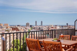 Ein Balkon mit Tisch und Stühlen, einem Getränk und einer Fruchtschale.