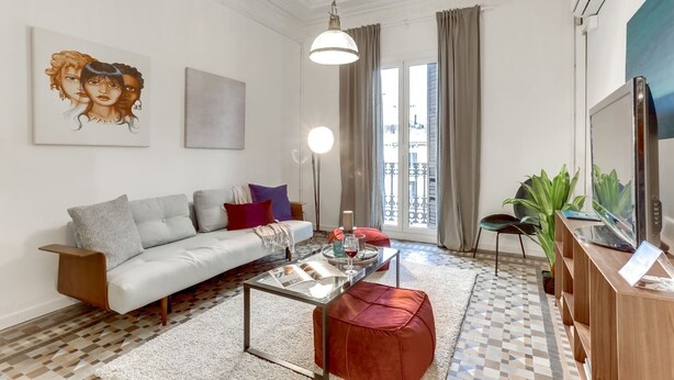 A modern living room with a sofa, coffee table, and a large window with curtains.