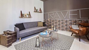Un salon moderne avec un canapé gris, un fauteuil en cuir, un tapis à motifs et un mur sur lequel est écrit le mot «VOYAGE».