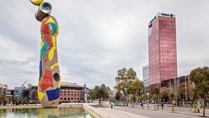 Een kleurrijk beeld in een openbaar plein, met een modern gebouw op de achtergrond.