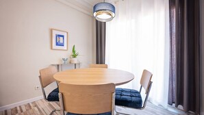 A modern dining area with a round table, four chairs, a hanging light fixture, a framed picture, and a potted plant. - Sweett | Charming in Sant Gervasi (Barcelona)