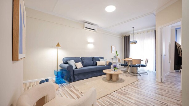 A modern living room with a sofa, coffee table, and a dining area with chairs. - Sweett | Charming in Sant Gervasi (Barcelona)