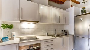 Una cocina moderna con armarios blancos, un refrigerador de acero inoxidable y un horno empotrado.