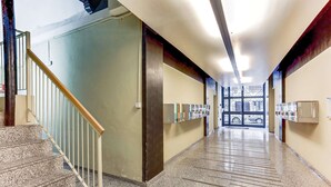 Un pasillo largo y estrecho con una escalera a la izquierda, que lleva a una puerta al final.
