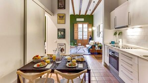 Una cocina pequeña con comedor, que incluye una mesa lista para el desayuno con platos, vasos y una jarrón.