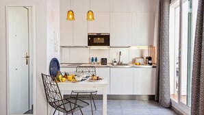 Cocina compacta con comedor, que incluye un armario blanco, un microondas, un fregadero y una mesa con platos y vasos.