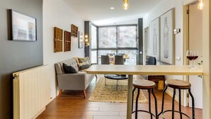 A modern kitchen with a dining area, featuring a central island, bar stools, and a view through large windows. - Sweett | Raul - Two Bedroom Apartment, Sleeps 4 (Barcelona)