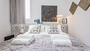 A modern bedroom with a patterned headboard, a large decorative mirror, and a fluffy rug.