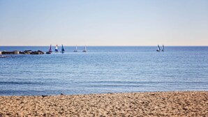 En strand med krystalklart hav og flere sejlbåde.