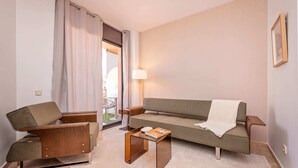 A living room with a sofa, armchair, coffee table, and a lamp. - Sweett | Cosy Ciutadella (Barcelona)