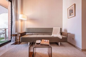 Un salon moderne avec un canapé, une table d’appoint, une lampe et un tableau encadré au mur.