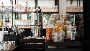 Zona de bar con una máquina de café, saleros y pimenteros, y varios frascos de aperitivos.