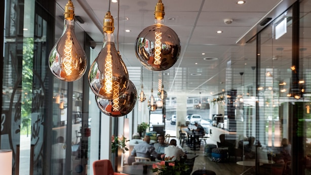 A modern interior with hanging spherical light fixtures and a seating area with tables and chairs. - B&B Hotel Zürich East Wallisellen (Wallisellen)