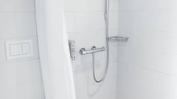 Une salle de bain moderne avec des toilettes blanches, une douche équipée d’un pommeau de douche amovible et un rideau de douche.