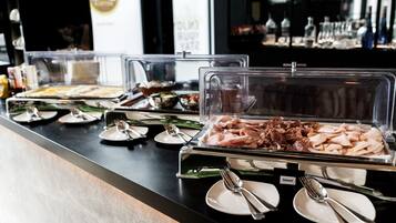 Ein Buffet mit verschiedenen Speisen, darunter geschnittene Fleischwaren und Käse, präsentiert in durchsichtigen Behältern.