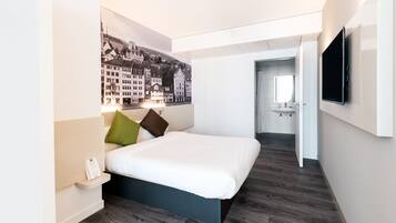 Una habitación de hotel moderna con una cama grande, un televisor de pantalla plana y un cartel con un paisaje urbano en la pared.