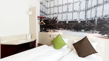 A hotel room with a bed, a desk, and a large window with a view of trees and a building.