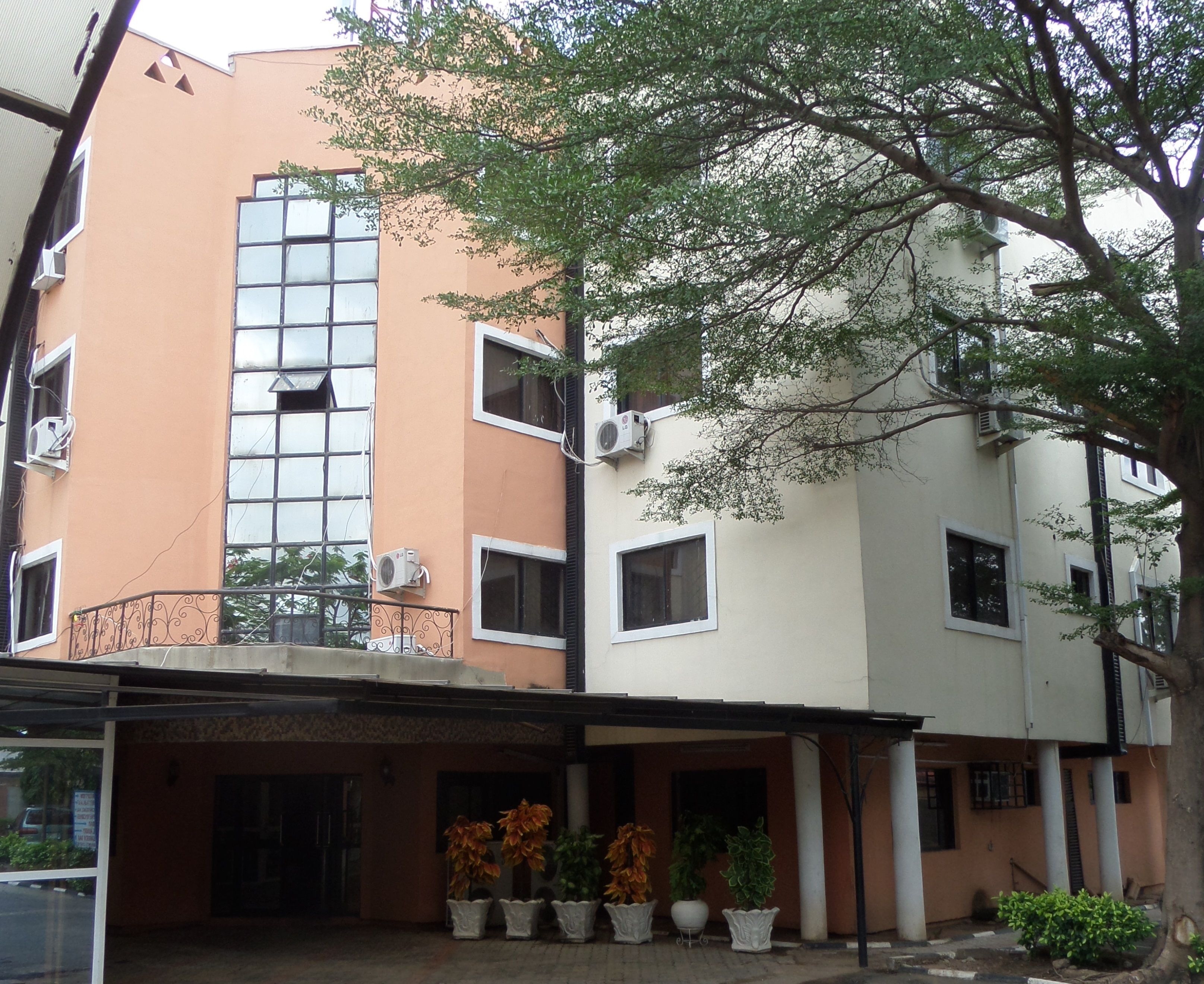 A multi-story building with a central atrium, air conditioning units, and potted plants.