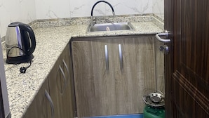 Een compacte keuken met een marmeren spatwand, een ingebouwd spoelbak en een gasfornuis.