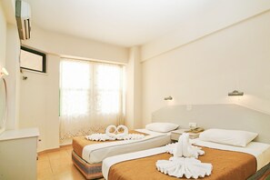 A hotel room with two beds, a large window with sheer curtains, a bedside table with a lamp, and a wall-mounted air conditioner. - Magi Apart Hotel (Alanya)