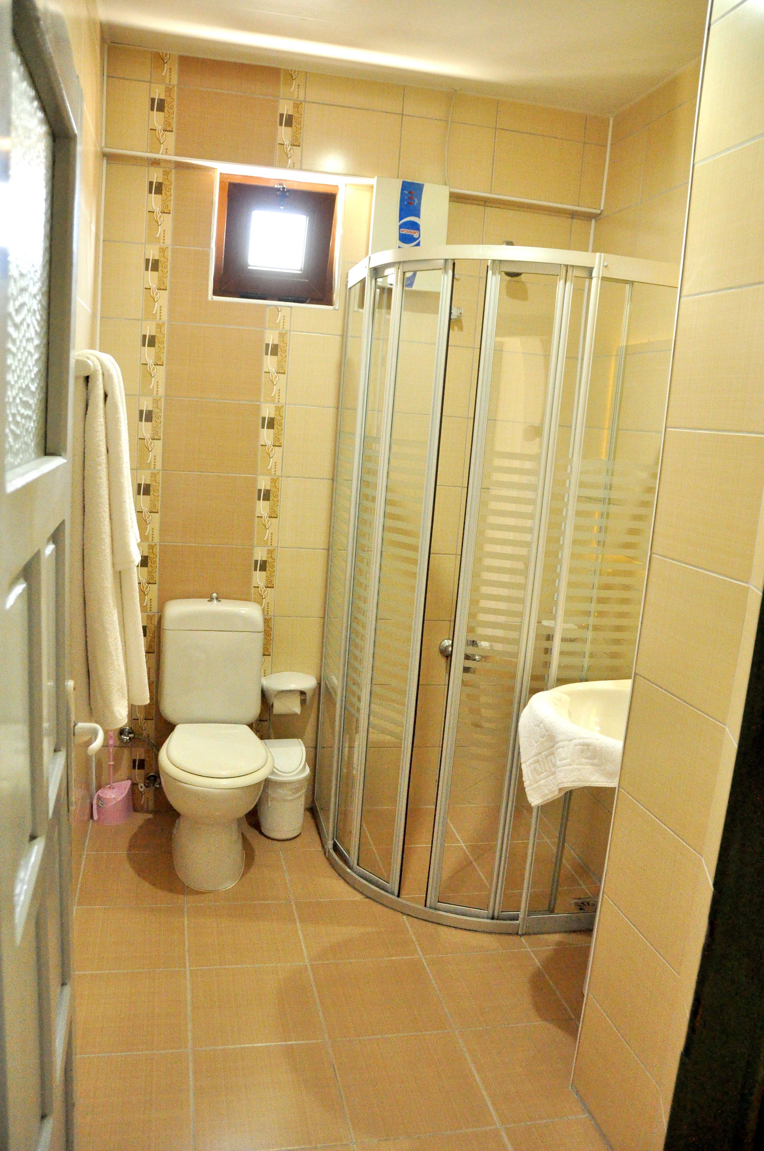 Un baño con inodoro, cabina de ducha y lavamanos.