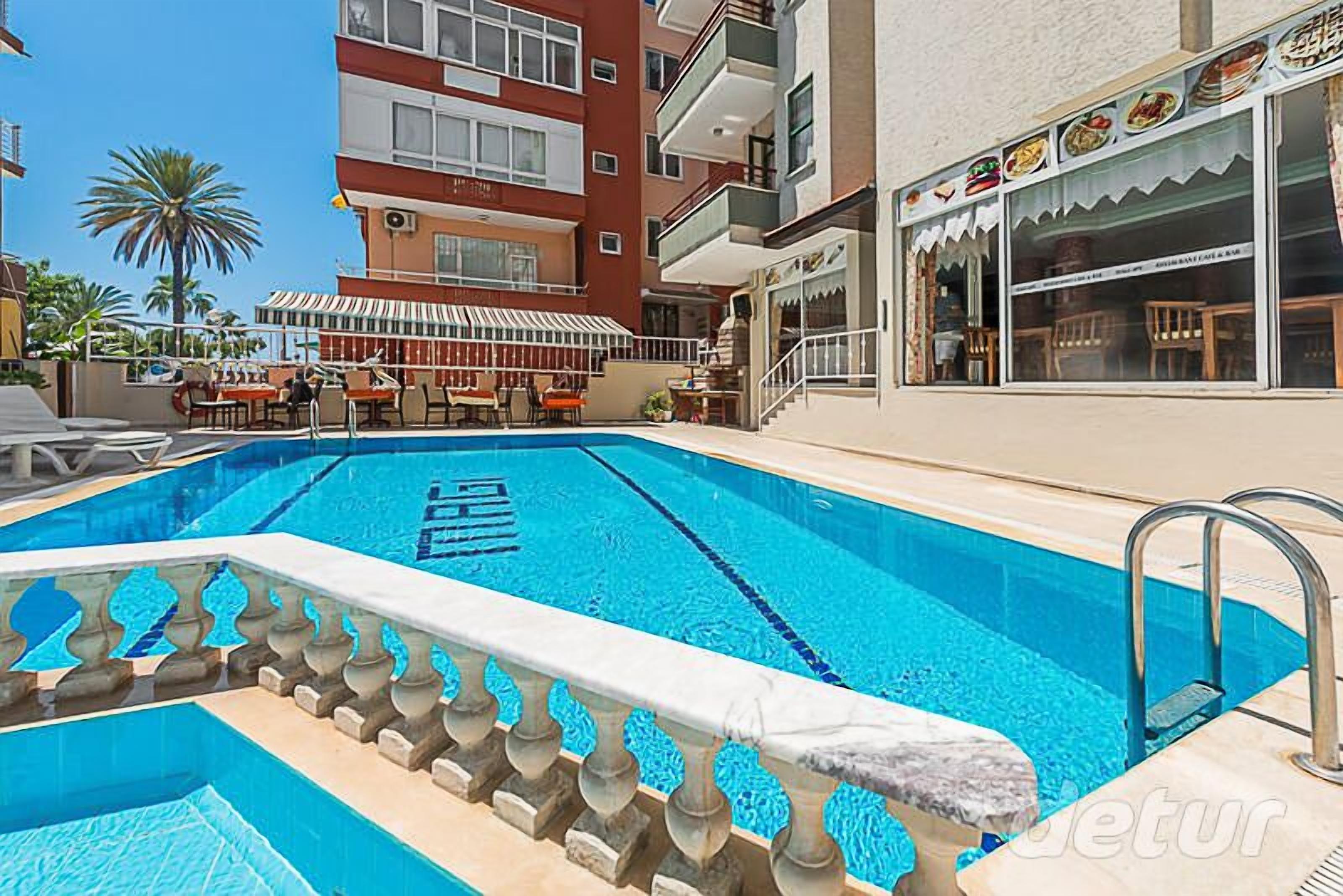 Ein Pool mit Steinbalustrade neben einem Gebäude mit Restaurant.