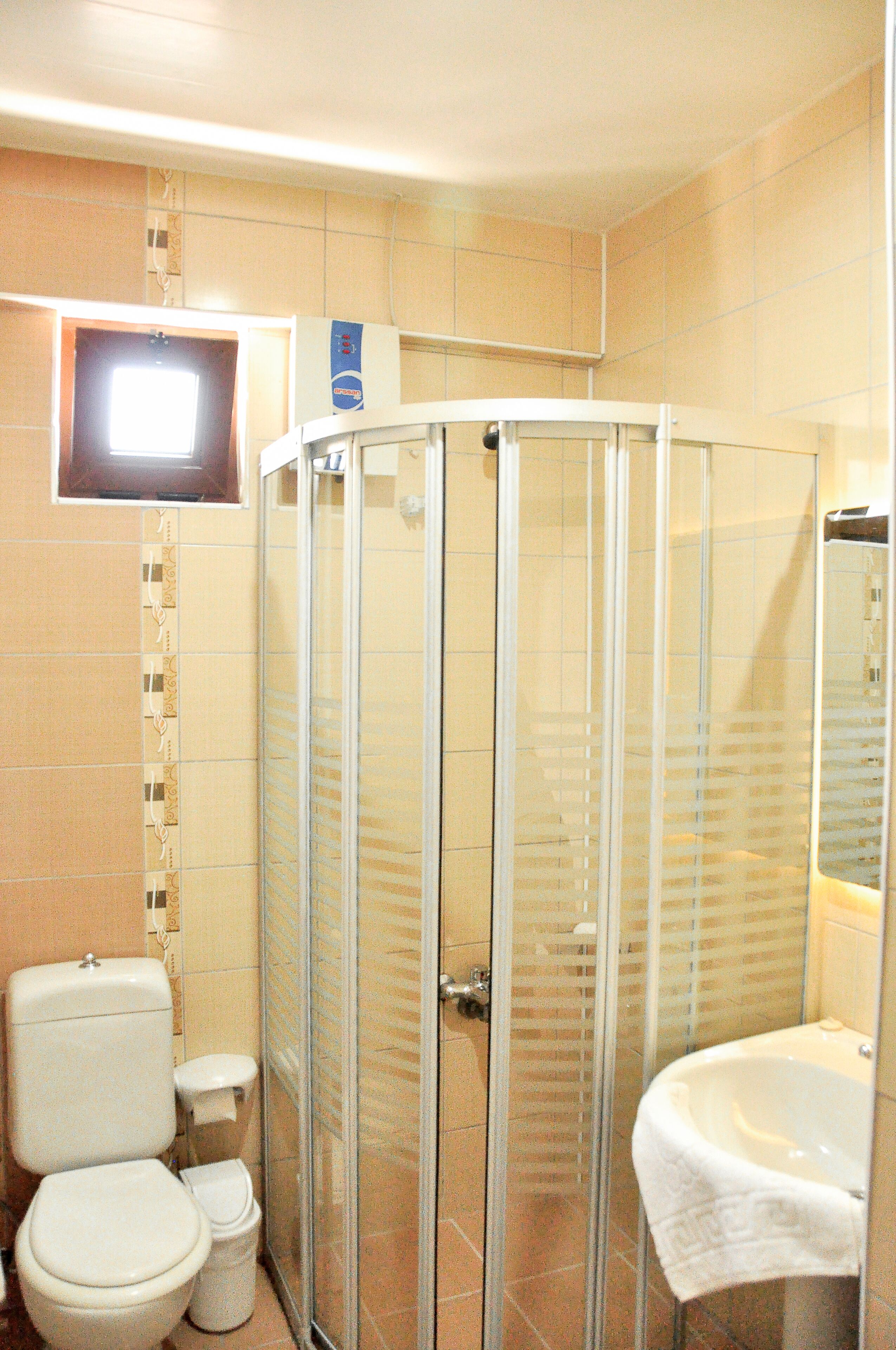A bathroom with a glass-enclosed shower, a toilet, and a sink.