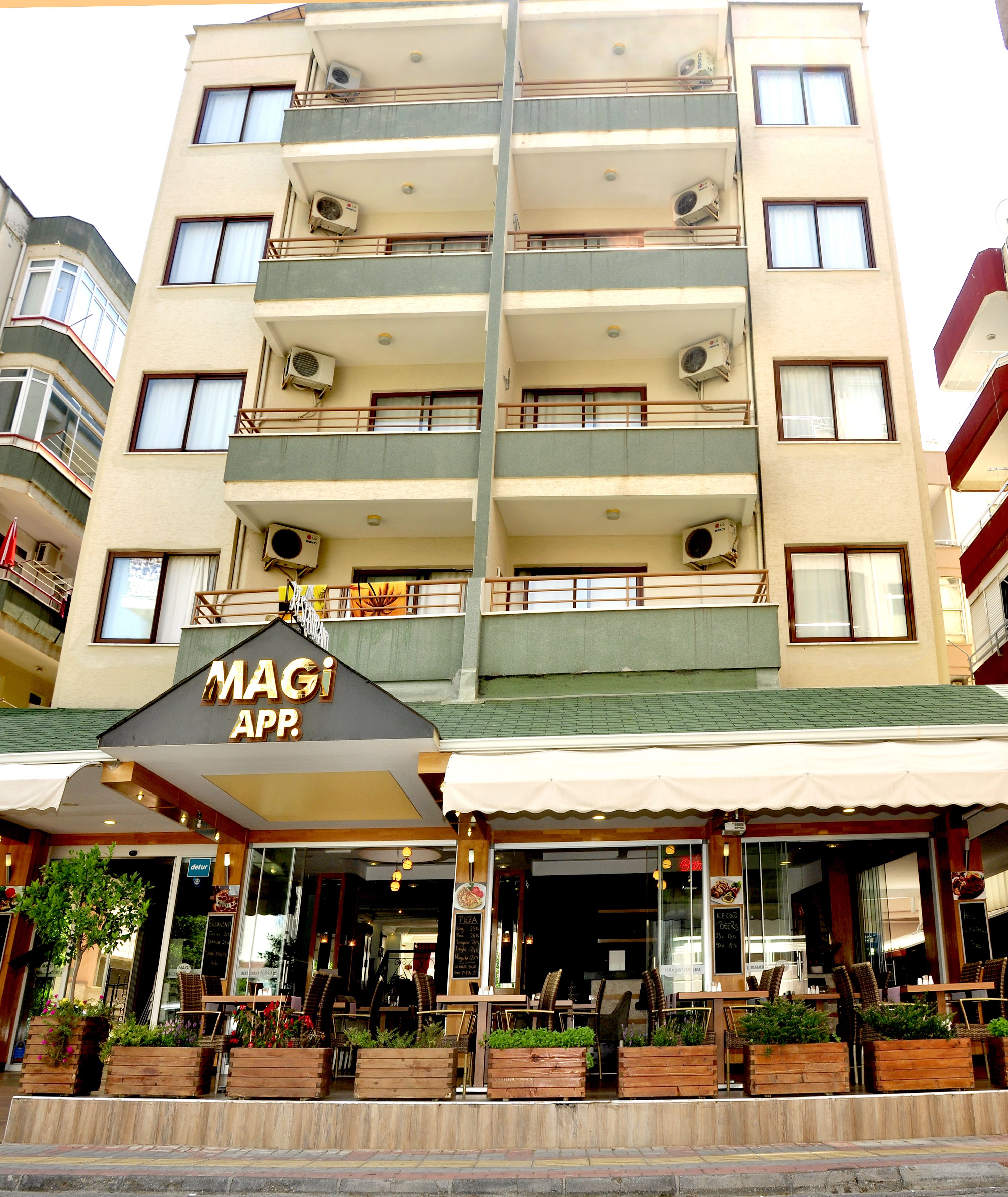 A multi-story hotel with balconies, outdoor seating, and a sign for 'MAGI APP.'