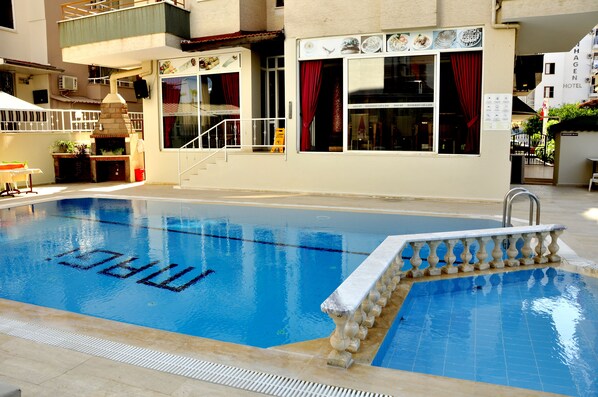 A swimming pool with a stone border and a brick oven.
